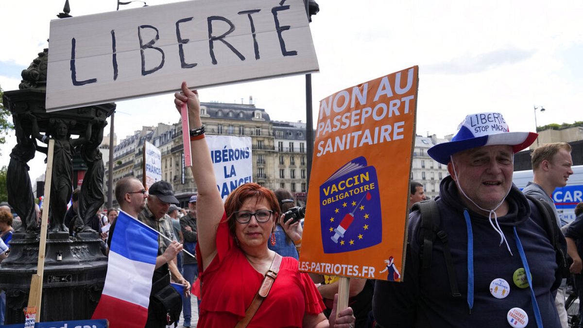 A protestor holds a sign which reads in French, "freedom" and "no to the Covid passport" as she attends a demonstration in Paris, France, Saturday, July 31, 2021. 