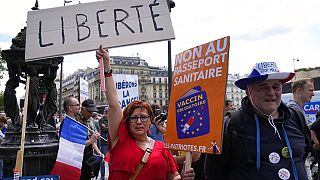 A protestor holds a sign which reads in French, "freedom" and "no to the Covid passport" as she attends a demonstration in Paris, France, Saturday, July 31, 2021. 