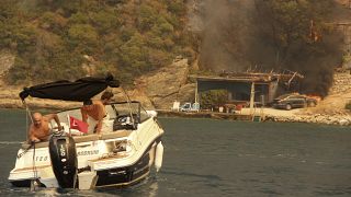 Dos personas evacuan en barco la zona de Mazi en Turquía ante el avance de las llamas