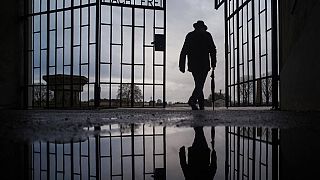 In this Sunday, Jan. 27, 2019 file photo a man walks through the gate of the Sachsenhausen Nazi death camp with the phrase 'Arbeit macht frei' (work sets you free)