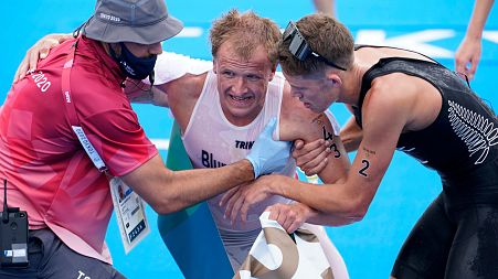 Kristian Blummenfelt being helped by other athletes after winning the 2020 Olympic triathlon.