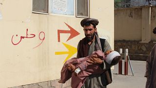 أفغاني ينقل طفلاً مصابًا إلى المستشفى بعد إصابته خلال قتال بين طالبان والحكومة في ولاية بادغيس شمال غرب أفغانستان