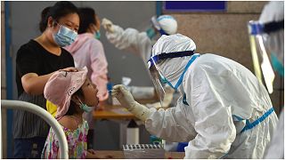 ممرضة صينية تأخذ من طفلة عينة اختبار للتأكد من عدم إصابتها بفيروس كورونا في أحد المراكز الطبية بمدينة نانجينع في مقاطعة جيانغسو غربي البلاد