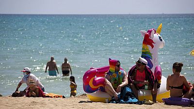 Turistas se bañan y toman el sol en una playa de Mallorca