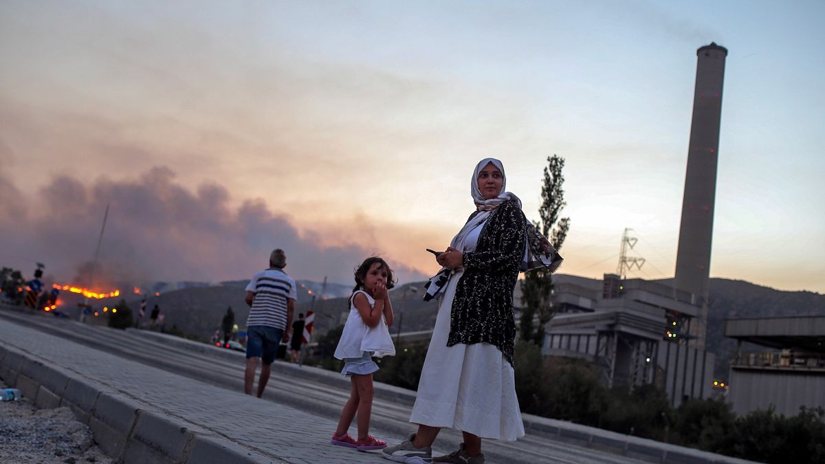 People stand in front of Kemerkoy Thermal Power Plant, right, as a wildfire approaches in the background, in Milas, Mugla, Turkey, Aug. 3, 2021. 