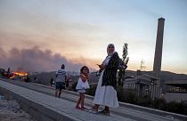 People stand in front of Kemerkoy Thermal Power Plant, right, as a wildfire approaches in the background, in Milas, Mugla, Turkey, Aug. 3, 2021.