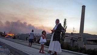 People stand in front of Kemerkoy Thermal Power Plant, right, as a wildfire approaches in the background, in Milas, Mugla, Turkey, Aug. 3, 2021. 