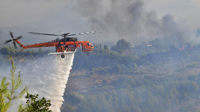 Ein Hubschrauber bekämpft ein Feuer nahe der antiken Olympiastätten