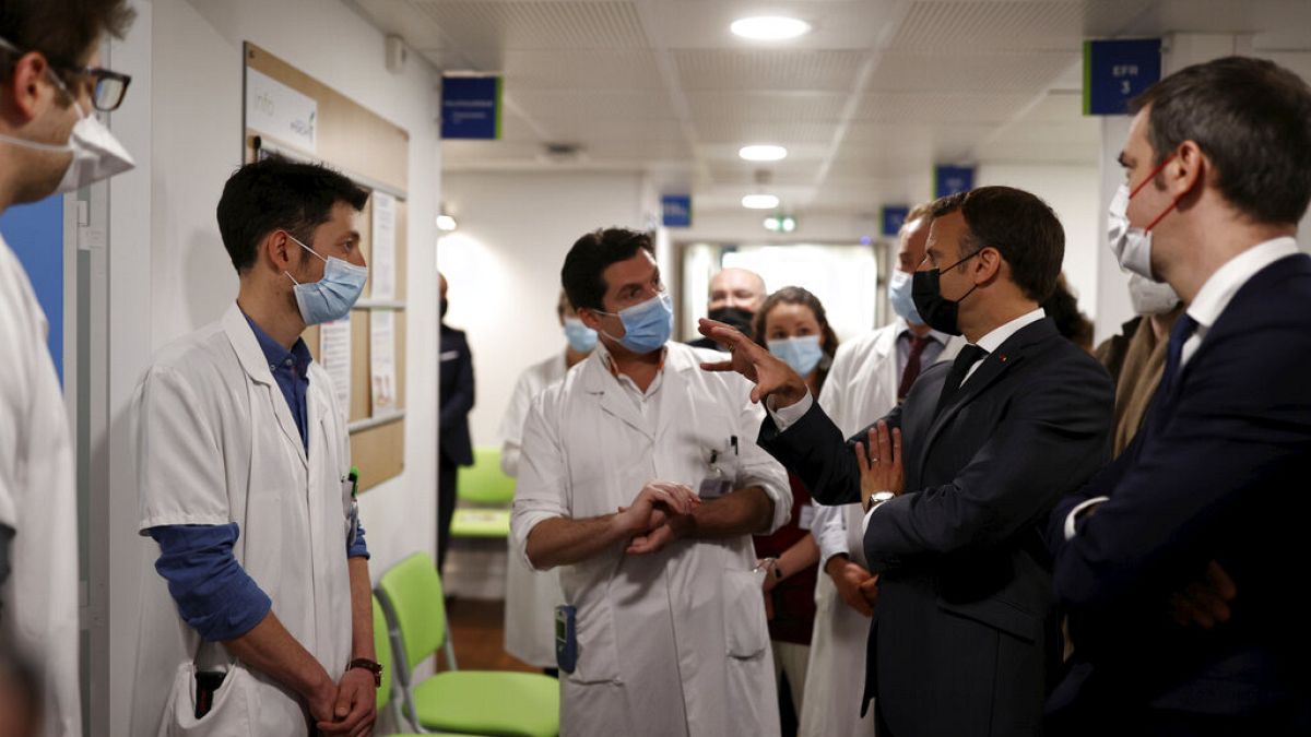 French President Emmanuel Macron talks with medical staff members as he visits the Pulmonology department at the Foch hospital