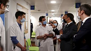 French President Emmanuel Macron talks with medical staff members as he visits the Pulmonology department at the Foch hospital