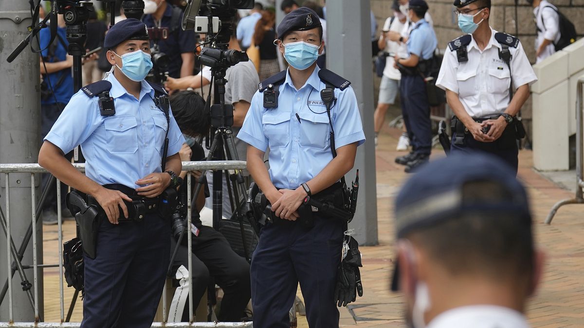 Police officers outside a court July 30, 2021, in Hong Kong, as pro-democracy demonstrator Tong Ying-kit exits after his sentencing for the violation of a security law.