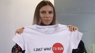 Kristsina Timanovskaïa, montrant un tshirt où il est écrit, en anglais, "Je veux juste courir", lors de sa conférence de presse à Varsovie, le 5 août