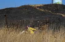 An Israeli firefighter attempts to extinguish a fire caused by rocket fired from Lebanon into Israeli territory near the northern Israeli town of Kiryat Shmona.
