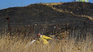 An Israeli firefighter attempts to extinguish a fire caused by rocket fired from Lebanon into Israeli territory near the northern Israeli town of Kiryat Shmona.