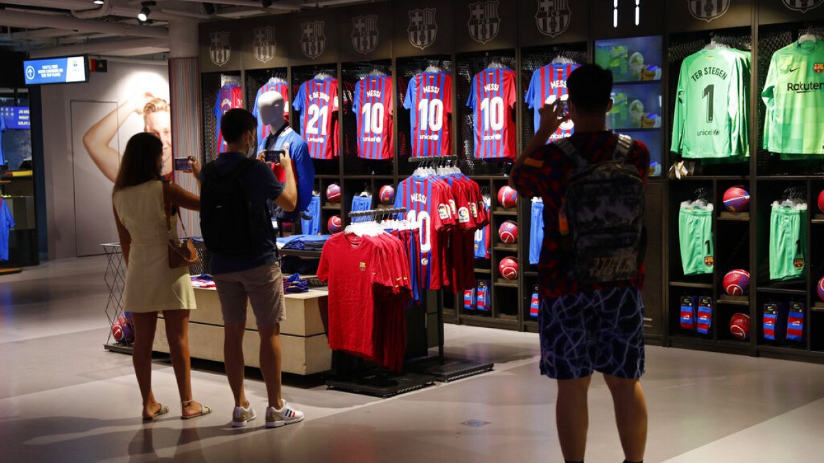 People take photos of Lionel Messi shirts on sale at the club's store before FC Barcelona club President Joan Laporta gives a news conference in Barcelona