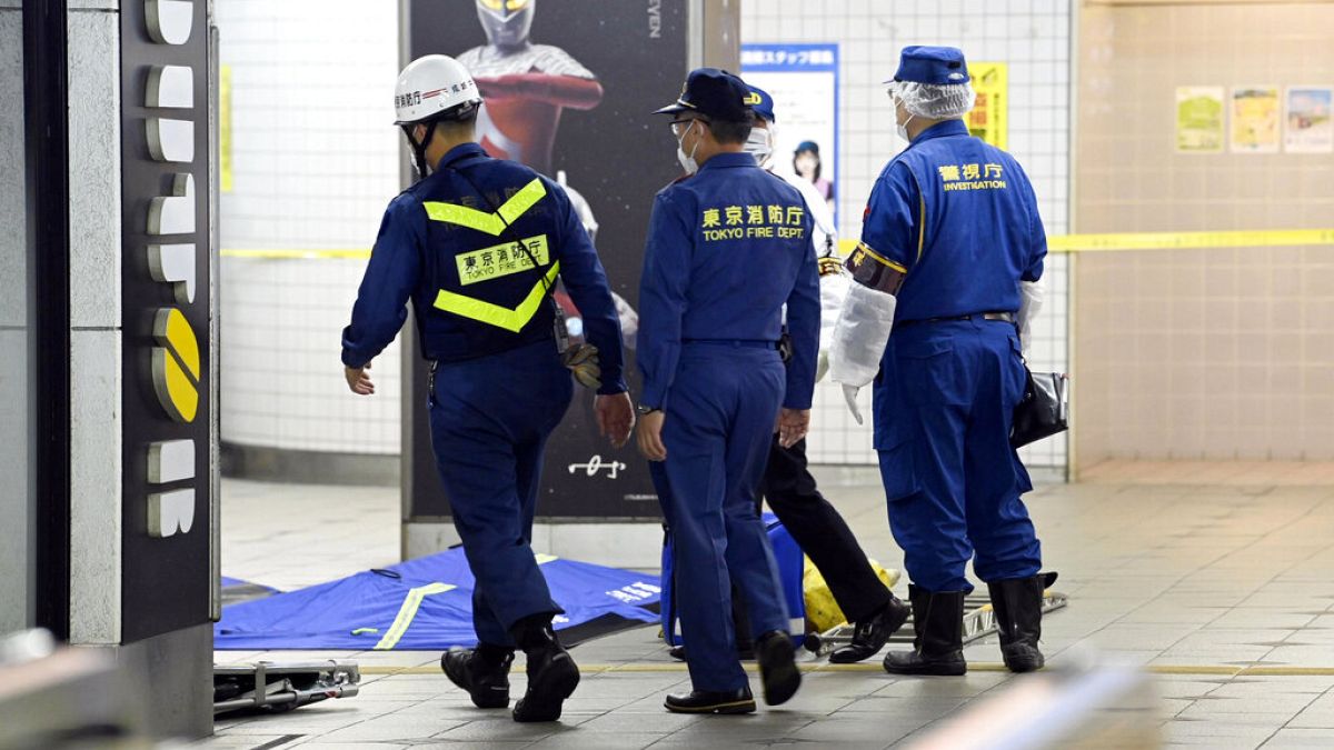 Tokyo Fire Department personnel and a police investigator, right, move toward a platform at Soshigaya Okura Station after stabbing on a commuter train