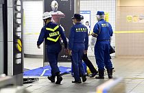 Tokyo Fire Department personnel and a police investigator, right, move toward a platform at Soshigaya Okura Station after stabbing on a commuter train