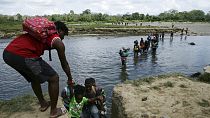 Migrants cross the Tuquesa river after a trip on foot through the jungle to Bajo Chiquito, Darien province, Panama, Wednesday, Feb. 10, 2021