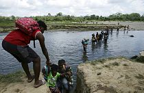 Migrants cross the Tuquesa river after a trip on foot through the jungle to Bajo Chiquito, Darien province, Panama, Wednesday, Feb. 10, 2021