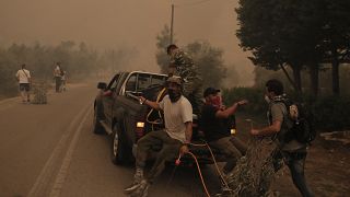 Πολίτες επιβιβάζονται σε υδροφόρο όχημα κατά τη διάρκεια της επιχείρησης κατάσβεσης της πυρκαγιάς στην περιοχή Πευκί στην Βόρεια Εύβοια