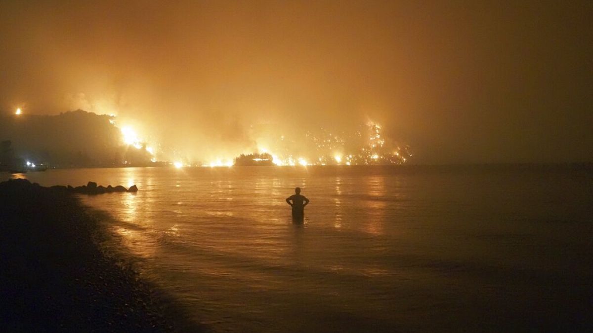 En esta foto de archivo fechada el viernes 6 de agosto de 2021, un hombre observa cómo los incendios forestales se acercan a la playa de Kochyli, en Grecia