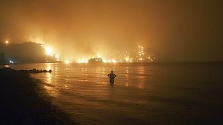 En esta foto de archivo fechada el viernes 6 de agosto de 2021, un hombre observa cómo los incendios forestales se acercan a la playa de Kochyli, en Grecia