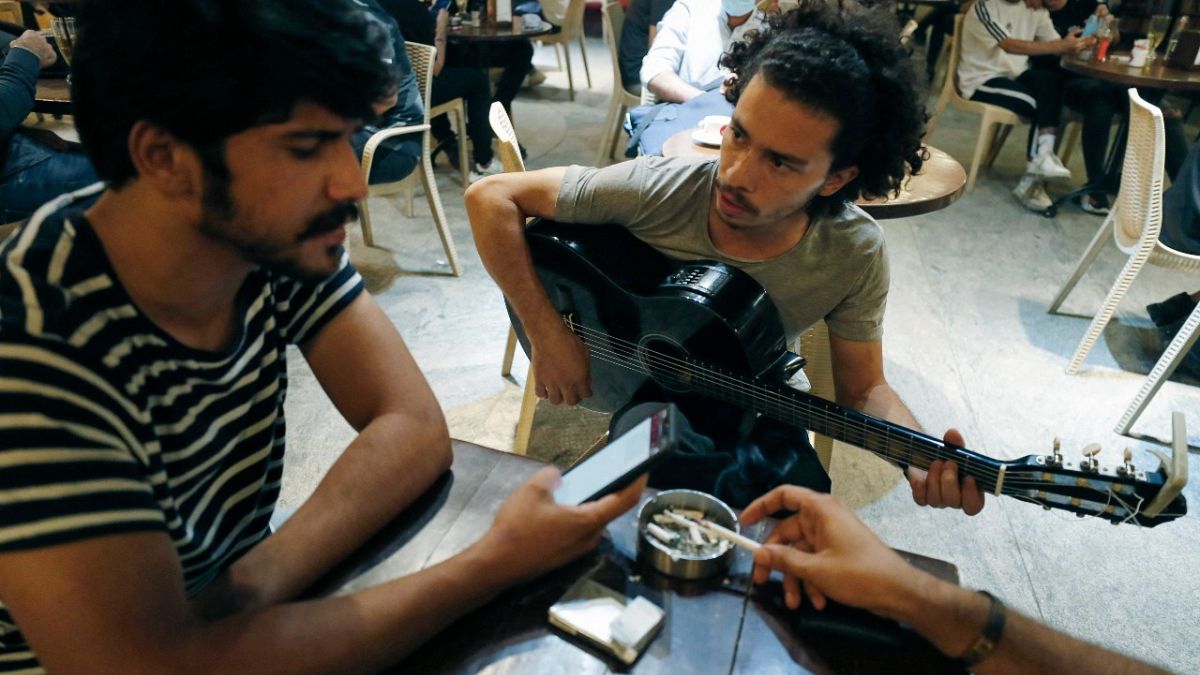 عازف الجيتار العراقي محمد، يلعب وهو يجلس مع أصدقائه في مقهى بالعاصمة بغداد، العراق.