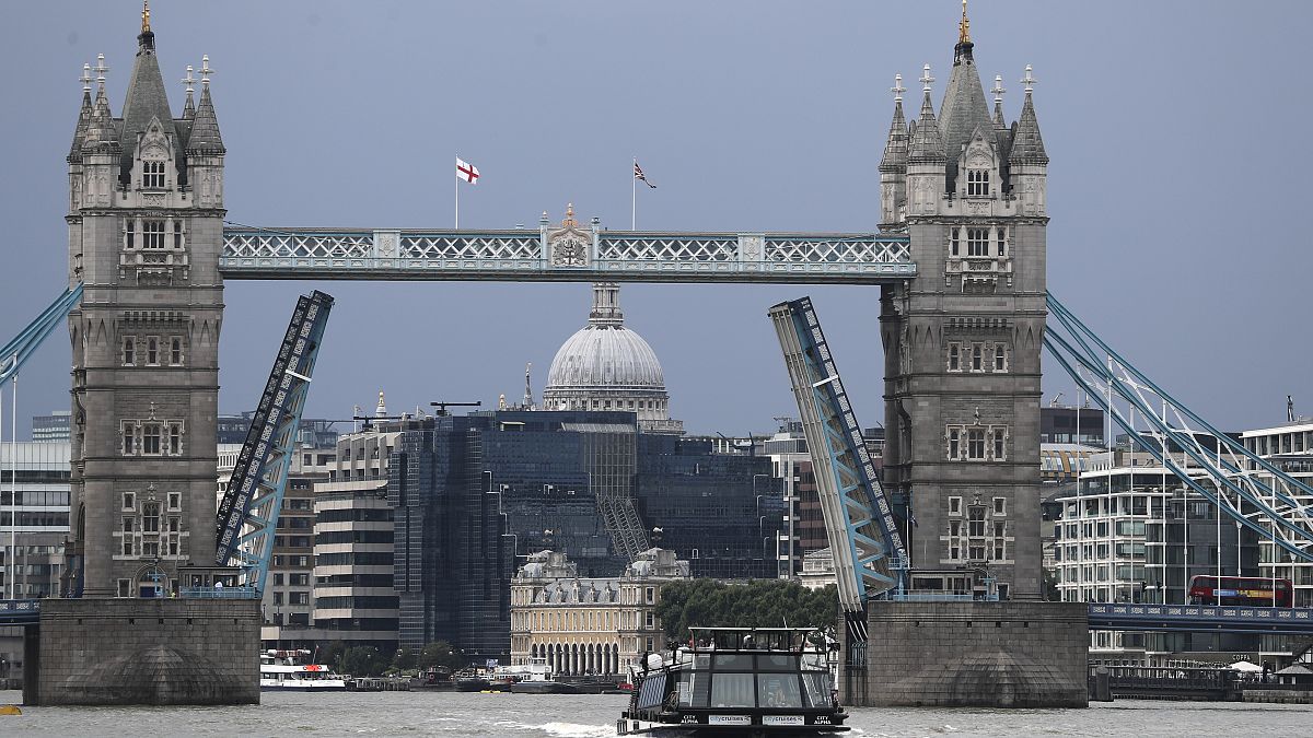 A boat sails down the River Thames in London, Monday Aug. 9, 2021 in front of Tower Bridge that is stuck in the fully open position due to a technical fault. 
