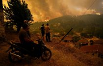 Az Évia szigetén fekvő Gouves lakó nézik a településhez közelítő lángokat egy dombról