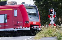 A Deutsche Bahn (DB) commuter train passes a level crossing with a red light in Roessing, Germany, Aug. 11, 2021.