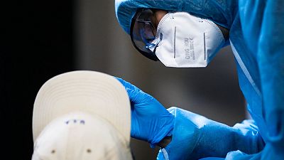 A nose swab is taken from a man for a SARS CoV-2 rapid test at the Corona Antigen Rapid test center at the 'KitKat-Club' in Berlin, Germany, Thursday, Dec. 17, 2020.