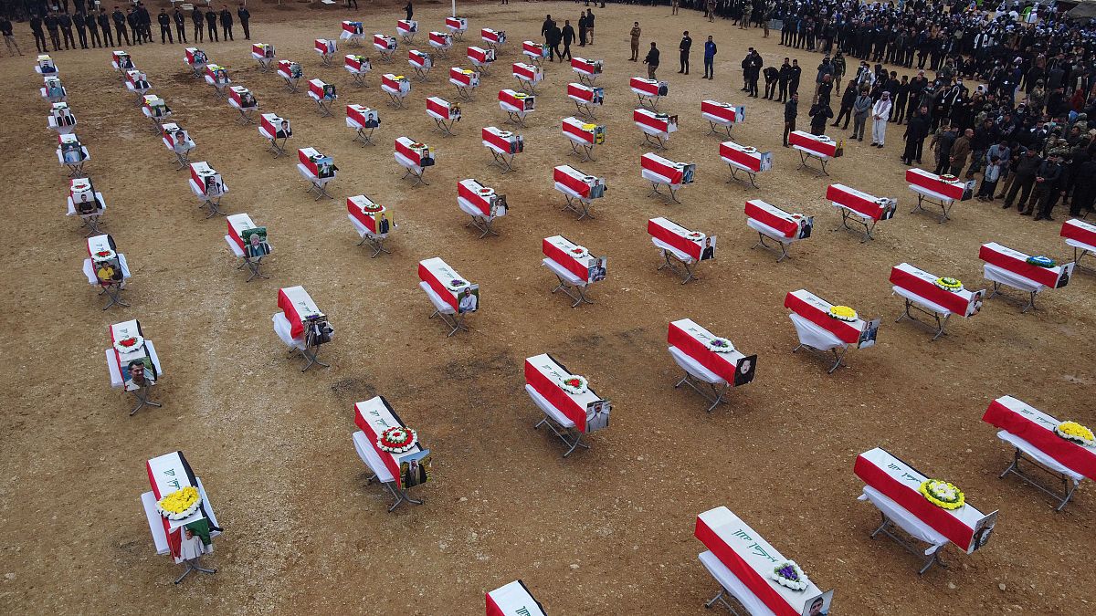 An aerial picture shows mourners gathering around coffins wrapped with the Iraqi flag during a mass funeral for Yazidi victims of the Islamic State (IS) group