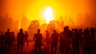 Local people gather during a wildfire next to the village of Kamatriades on Greece's Evia island on August 9, 2021