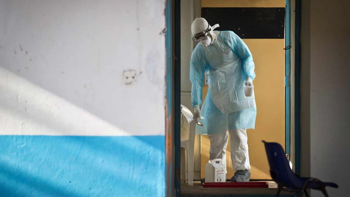 A medical worker cleans a cup used by a man quarantined after coming into contact with a carrier of the Marburg Virus, Uganda, Oct. 8, 2014.