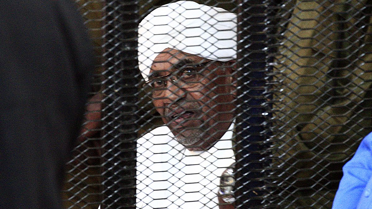 الرئيس السوداني المخلوع عمر البشير ينظر من قفص المدعى عليه خلال افتتاح محاكمة فساد في الخرطوم.