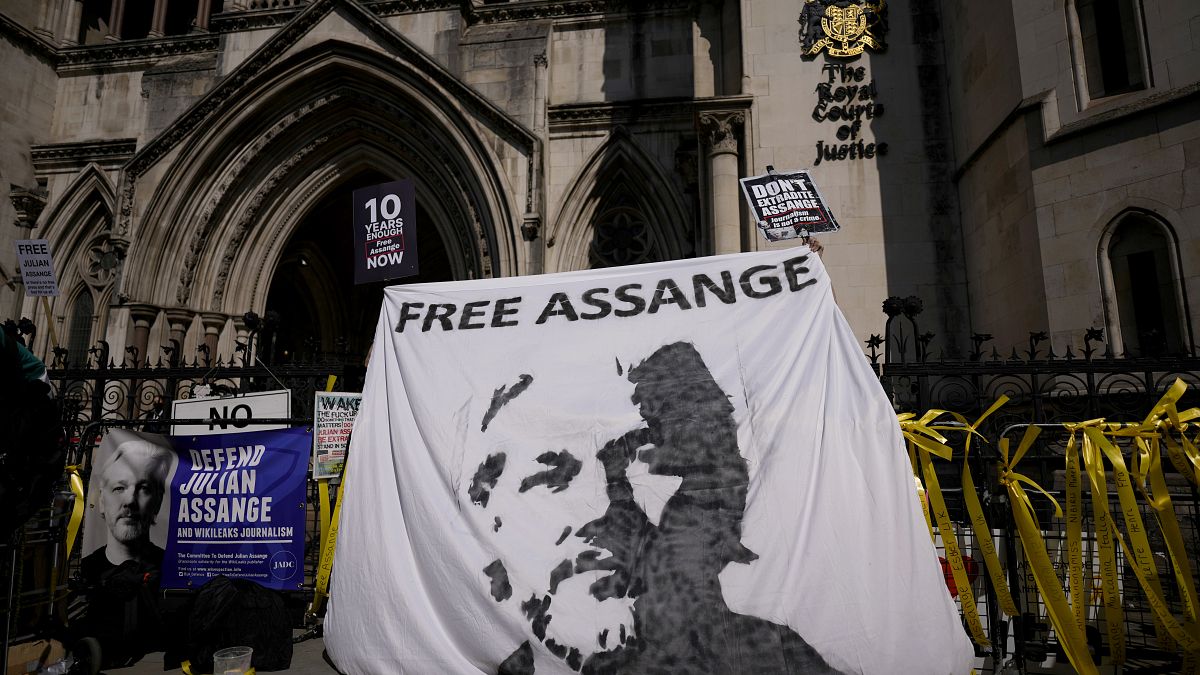 Supporters of WikiLeaks founder Julian Assange hold up a banner as they protest, during the first hearing in the Julian Assange extradition appeal, at the High Court in London