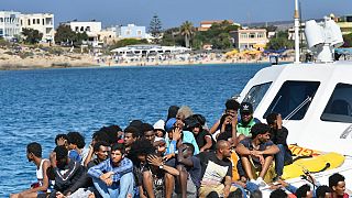 Migrants from Tunisia and Lybia arrive onboard of an Italian Guardia Costiera (Coast Guard) boat in the Italian Pelagie Island of Lampedusa on August 1, 2020.