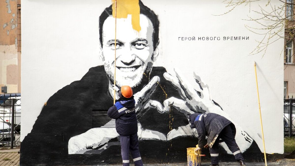 Municipal workers paint over graffiti of Russia's imprisoned opposition leader Alexei Navalny in St. Petersburg, Russia, Wednesday, April 28, 2021