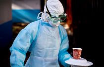 Oct. 8, 2014 photo, a medical worker carries a meal to a man being quarantined after coming into contact  with a carrier of the Marburg Virus