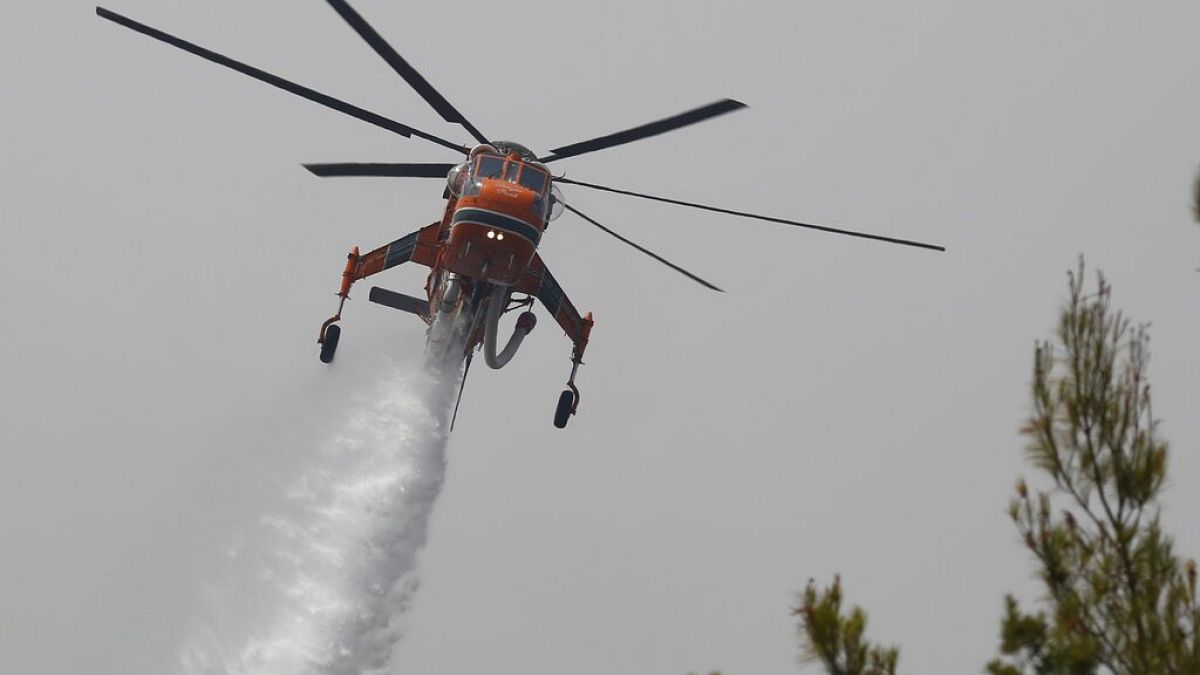 An helicopter drops water over a fire in Galatsonas village on Evia island, about 184 kilometers (115 miles) north of Athens, Greece, Wednesday, Aug. 11, 2021.