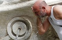 Un uomo si rinfresca in una fontana romana