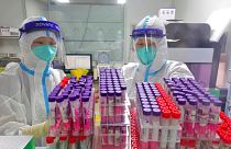 Workers handle swab samples for COVID-19 test at a hospital lab in Yantai in eastern China