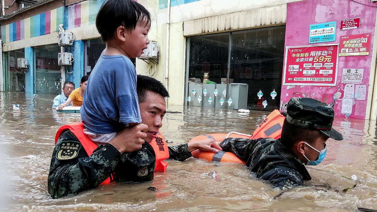 عمال الإنقاذ ينجدون طفلاً من منطقة غارقة في الفيضانات بعد هطول أمطار غزيرة في سويزهو بمقاطعة هوبي بوسط الصين.