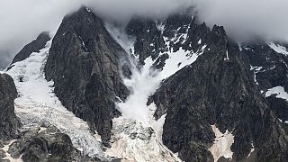 This picture taken in the Mont Blanc Massif, on August 3, 2021 shows a serac raising a snow cloud as falls downstream from Grandes Jorasses.