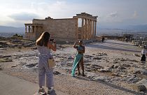 Туристы фотографируются на фоне Парфенона в афинском Акрополе