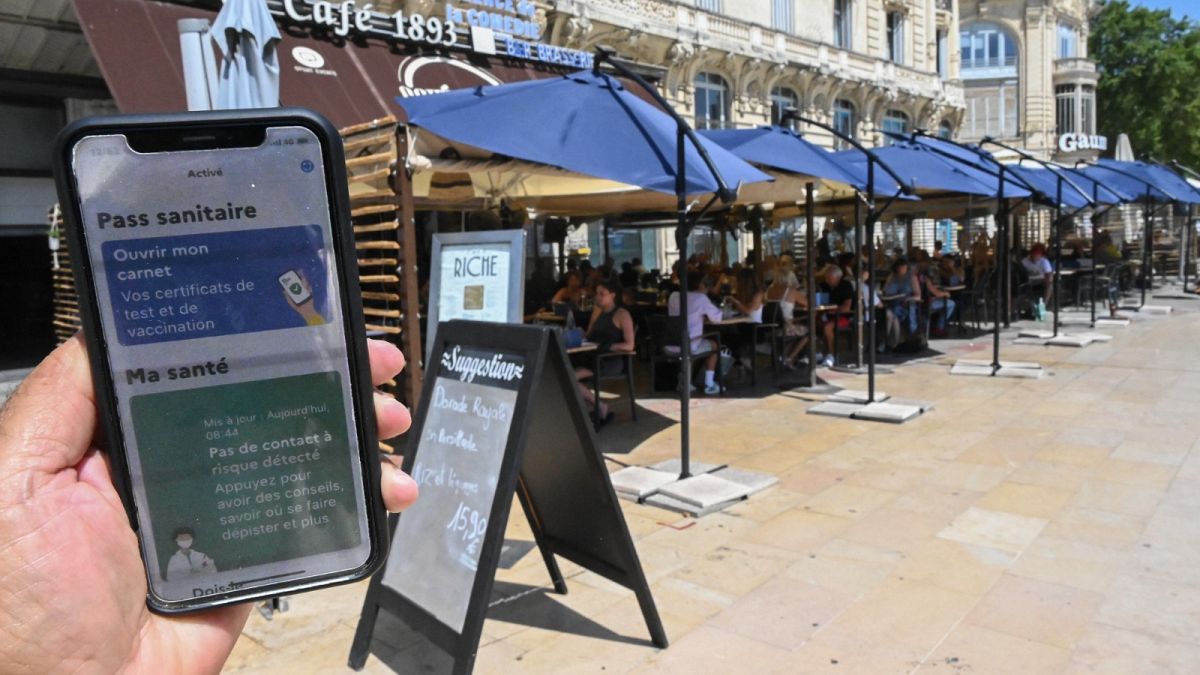رجل يعرضُ الشهادة الصحية الرقمية المحمّلة على هاتفه الذكي أمام أحد المطاعم في فرنسا.
