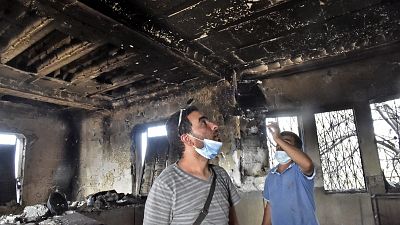Algerians inspect the damage at their home due to forest fires.