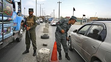 Afghan policemen stand guard at a checkpoint along the road in Kabul on August 14, 2021. 