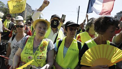 Demonstrators wearing yellow vests march in Paris on Saturday, Aug. 14, 2021.