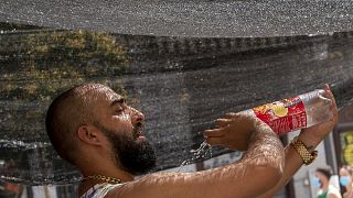 A vendor of a stall in the Rastro flea market tries to cool himself by pouring water over his body during a heatwave in Madrid